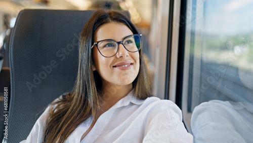 Free Download Young beautiful hispanic woman smiling happy looking through the window inside train wagon - GFXLoad