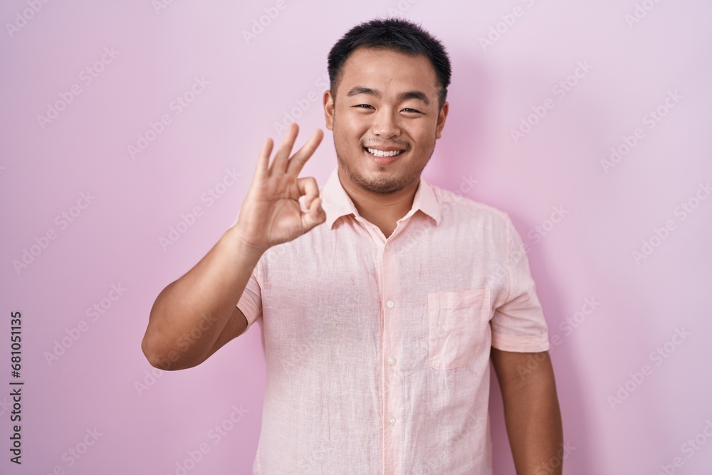 Chinese young man standing over pink background showing and pointing up with fingers number three while smiling confident and happy. Chinese young man standing over pink background showing and pointing up with fingers number three while smiling confident and happy.