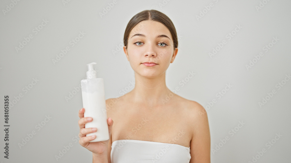 Young beautiful girl holding cream bottle over isolated white background Young beautiful girl holding cream bottle over isolated white background