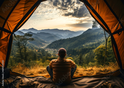 Male tourist view from the back sitting in a tent and admiring the view of the mountains © Kseniya