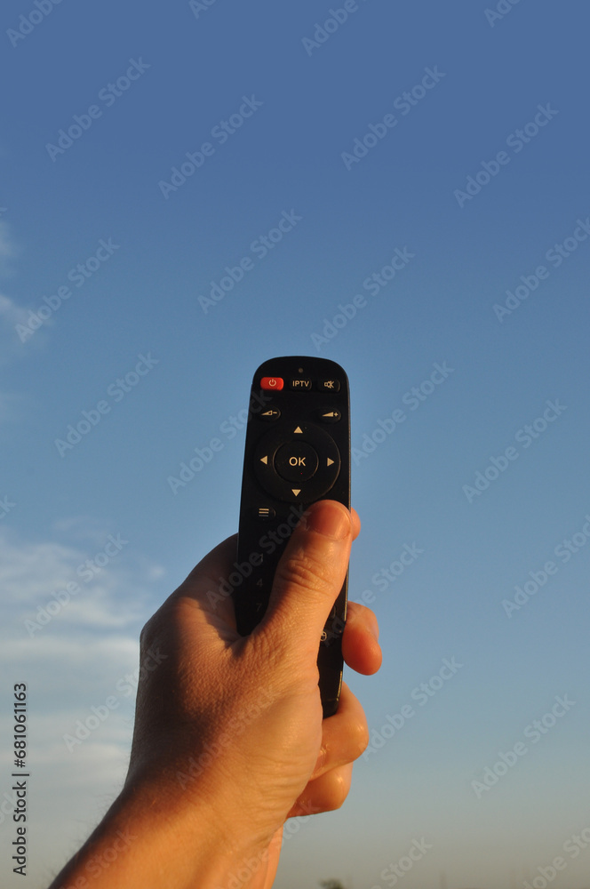 Fototapeta premium mão segurando controle da tv apontando para o céu 