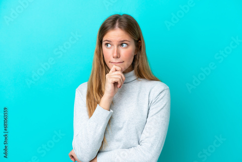 Young blonde woman isolated on blue background having doubts and thinking