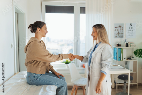 Teenage patient arriving at appointment with doctor, shaking hands with female pediatrician, physician. Teen girl have consultation, first visit with gynecologist. Concept of preventive health care photo