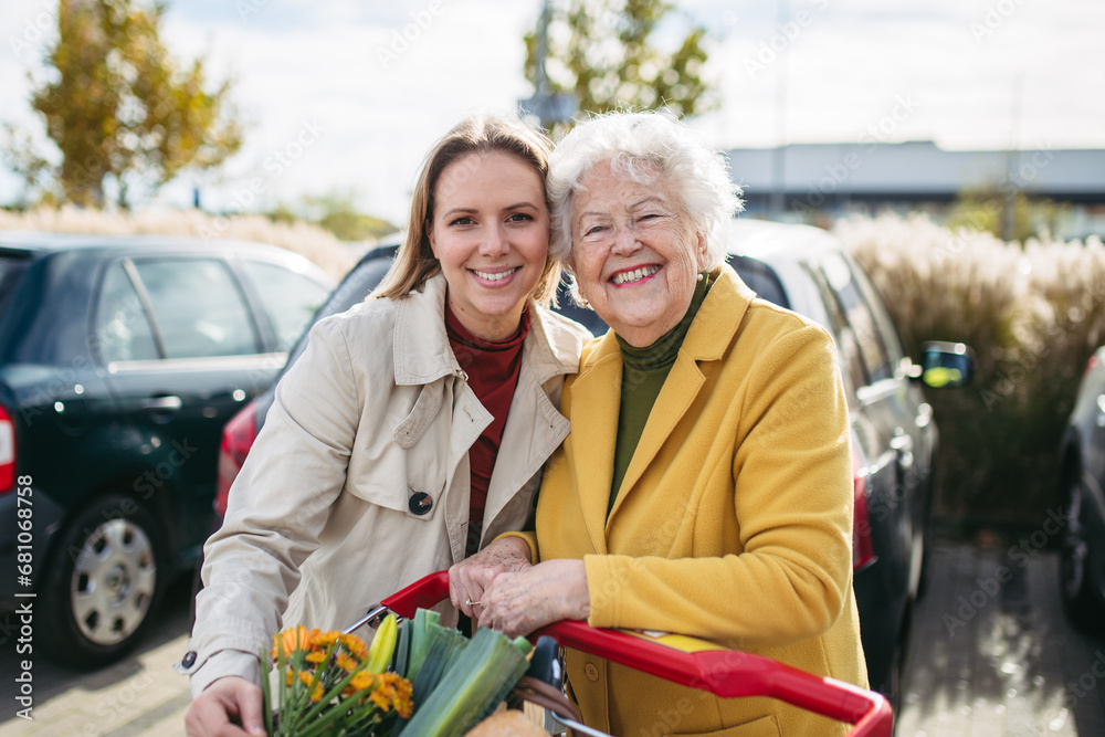 Φωτογραφία Mature granddaughter helping grandmother load groceries in to the car