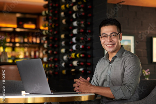 Portrait of smiling entrepreneur working on laptop at table in restaurant