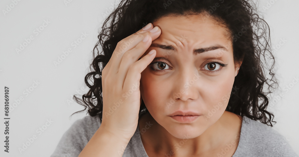 Young woman touching forehead, having headache, migraine or depression, worried about problem, feeling stressed, suffering from sadness, touching face, feeling sick, tired, thinking over bad news