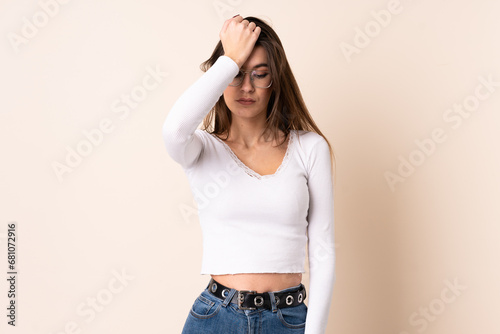 Young woman over isolated beige background with headache