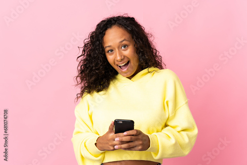 Teenager cuban girl isolated on pink background surprised and sending a message