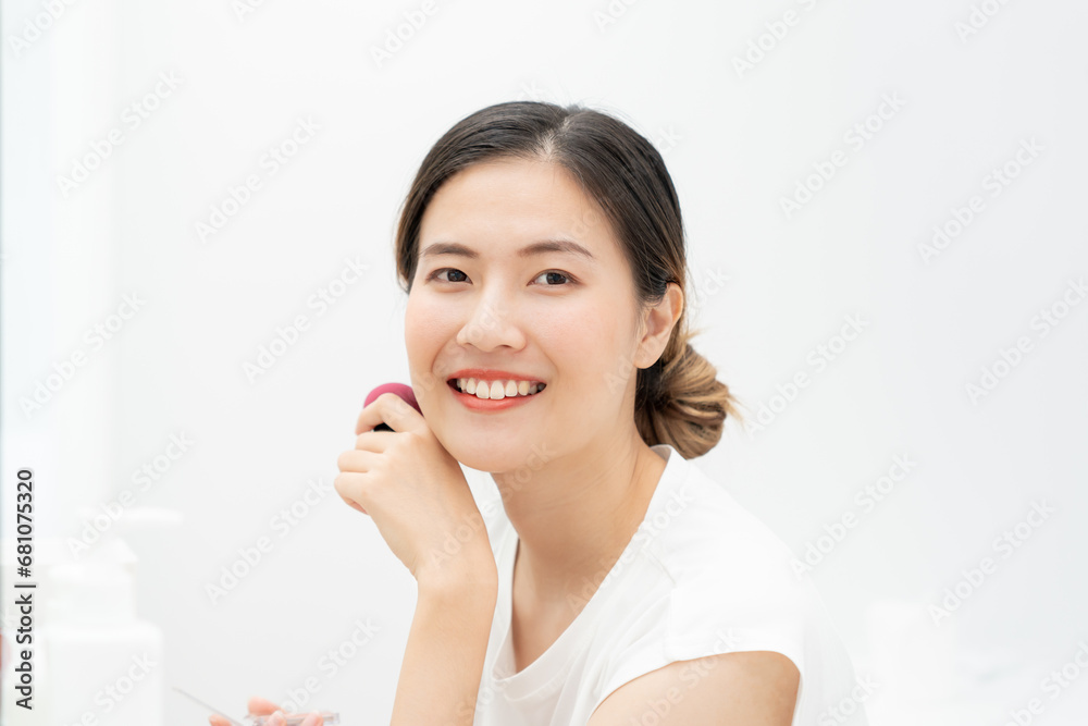 Beautiful Asian woman sit in front of a mirror and smile on makeup. face of a healthy woman applying makeup. Advertisement, lifestyle , cosmetics, makeup accessories, beauty activity, beautician Beautiful Asian woman sit in front of a mirror and smile on makeup. face of a healthy woman applying makeup. Advertisement, lifestyle , cosmetics, makeup accessories, beauty activity, beautician