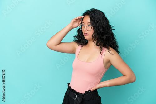 Young asian woman isolated on blue background with surprise expression while looking side © luismolinero