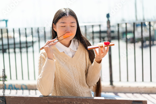 Young Chinese woman holding sashimi at outdoors photo