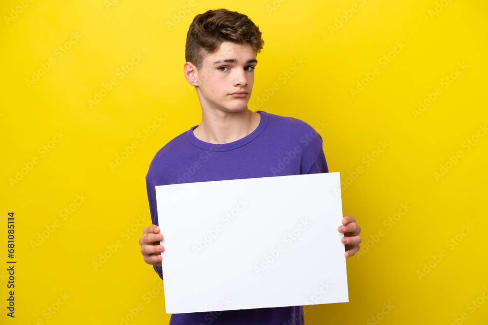 Teenager Russian man isolated on yellow background holding an empty placard Teenager Russian man isolated on yellow background holding an empty placard