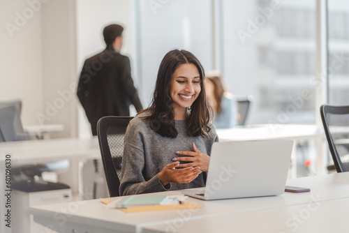 Smiling indian business woman having laptop video call, working online from modern office photo