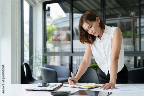 Free Download Middle age asian woman working on documents data at contemporary office. - GFXLoad