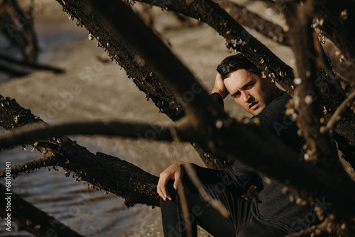 Handsome young man sitting on autumn depressive beach photo