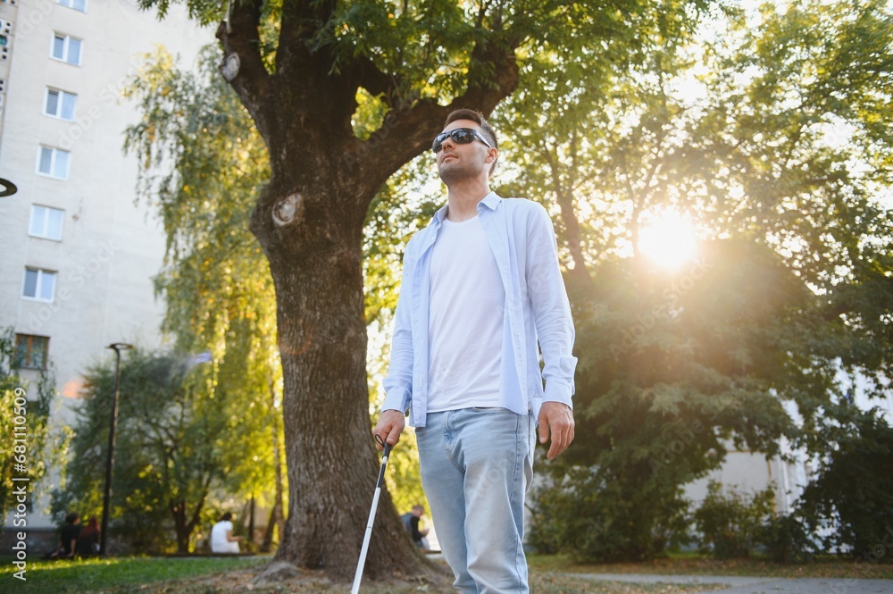 Young handsome blinded man walking with stick in town Young handsome blinded man walking with stick in town