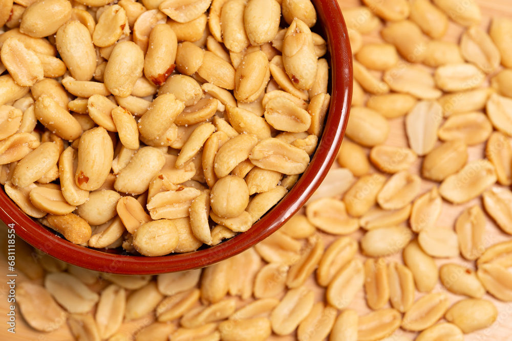 Salted peanuts in bowl in selective focus and out of focus. Peeled roasted peanuts close-up, top view. Salted peanuts in bowl in selective focus and out of focus. Peeled roasted peanuts close-up, top view.
