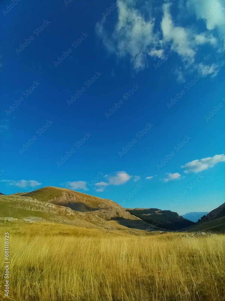Beautiful valley with hills and mountains in the background under the blue sky