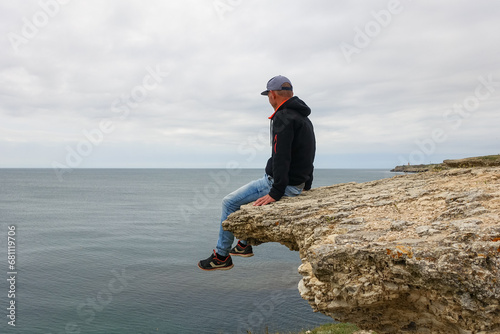 A man on Cape Tarkhankut. The rocky coast of the Dzhangul Reserve in the Crimea. Turquoise sea water. Rocks and grottoes of Cape Tarkhankut on the Crimean peninsula.