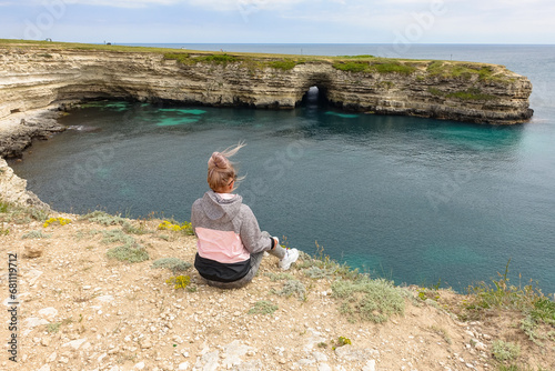 The girl at Cape Tarkhankut. The rocky coast of the Dzhangul Reserve in the Crimea. Turquoise sea water. Rocks and grottoes of Cape Tarkhankut on the Crimean peninsula. photo