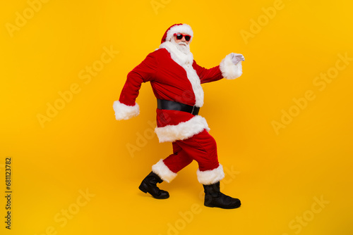 Full size profile portrait of eccentric aged santa claus sneaky walking christmas time isolated on yellow color background