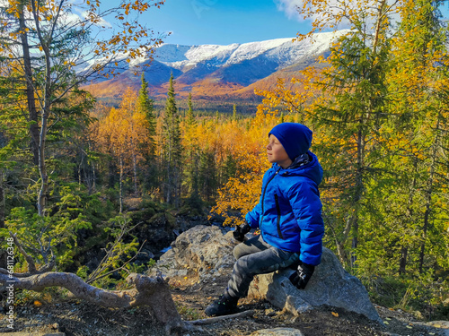 A boy on the background of an autumn Arctic landscape in the Khibiny mountains. Kirovsk, Kola Peninsula, Polar Russia. Autumn colorful forest in the Arctic, mountain hikes and adventures.