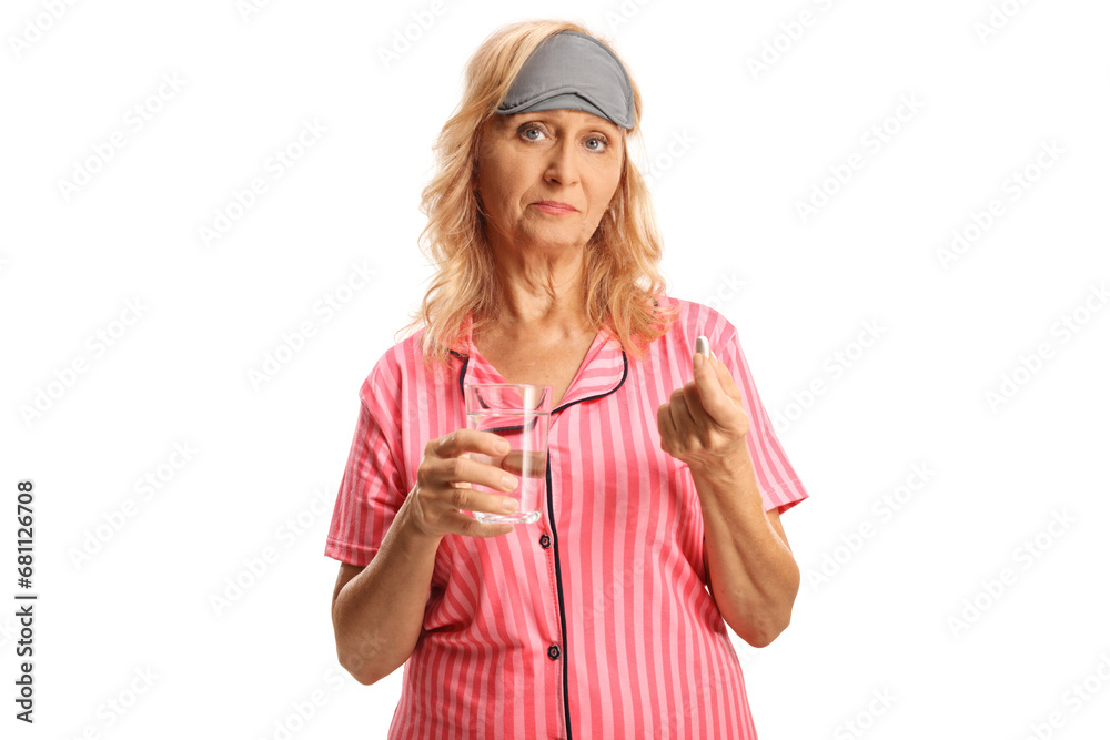 Sad mature woman in pajamas holding a pill and a glass of water Sad mature woman in pajamas holding a pill and a glass of water
