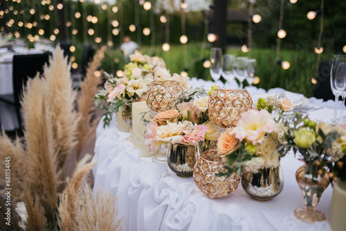 Close up of a wedding table decoration with purple, yellow and white flowers, reeds, candles. Wedding outdoor and floristic concept