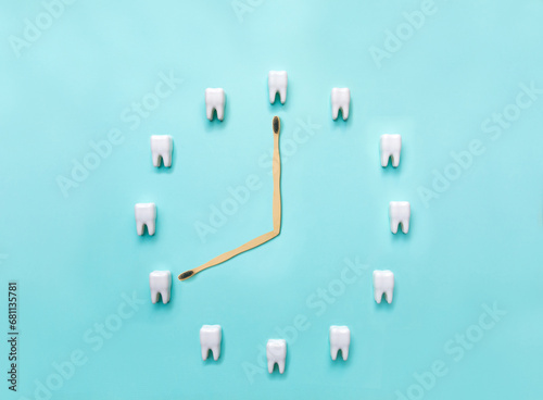A clock made of plastic models of teeth on a blue background and a toothbrush. Flat lay. Dentistry. Place for text. Oral health and dental examination of teeth. Stomatology. Concept of dental health.