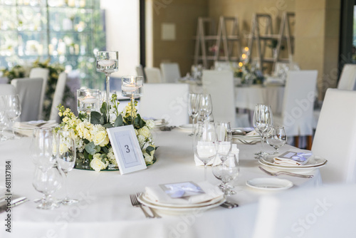  Wedding decorations. Served wedding table with decorative fresh white flowers and candles. Celebration details. flower composition roses plates and candles in candlesticks