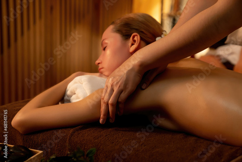 Caucasian woman customer enjoying relaxing anti-stress spa massage and pampering with beauty skin recreation leisure in warm candle lighting ambient salon spa at luxury resort or hotel. Quiescent