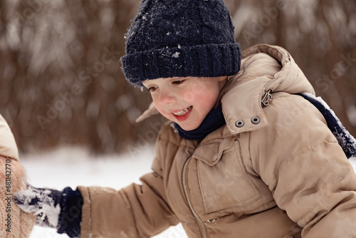 Little boy holding his mother's hand, walking on the street in winter, warm clothing. Happy winter time outdoor