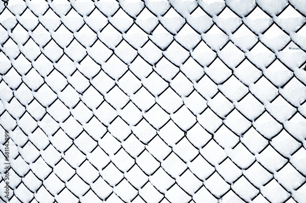A mesh fence covered with freshly fallen clean snow,. A mesh fence covered with freshly fallen clean snow,.