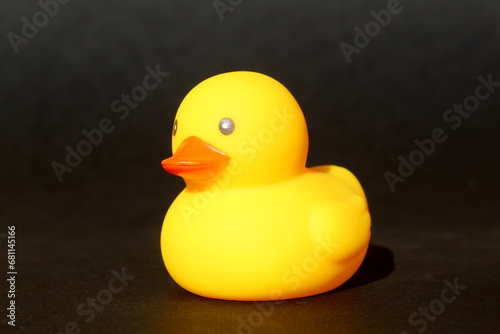 A yellow duck stands on a black background.