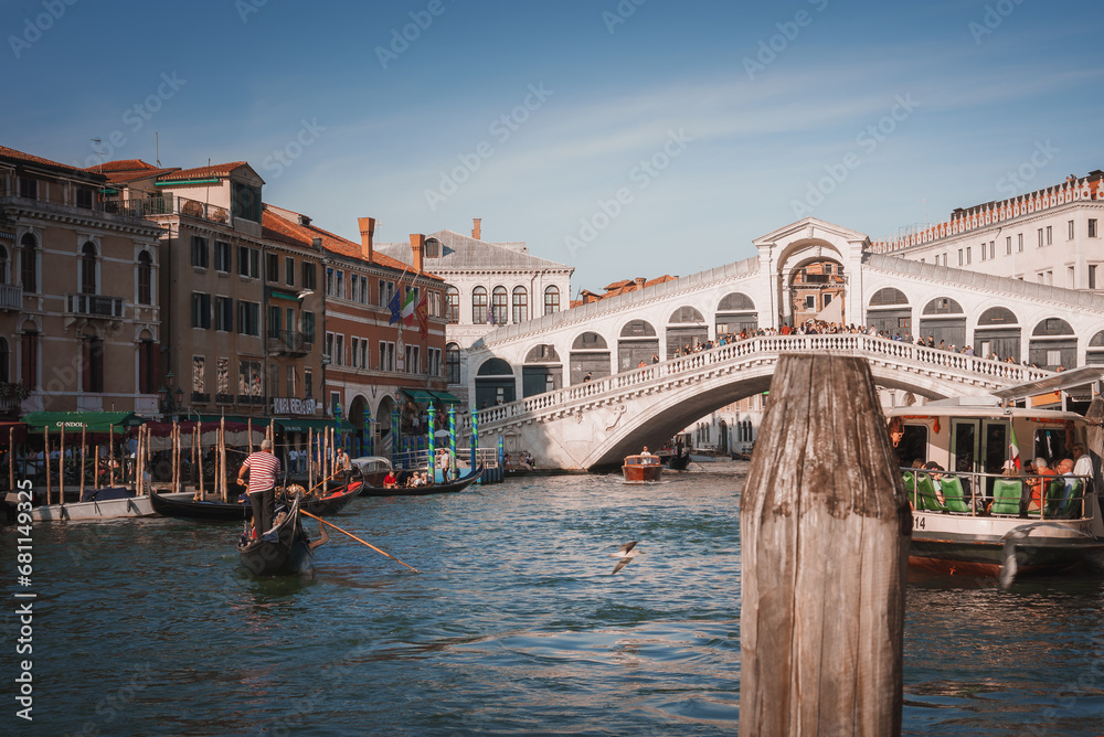 Scenic view of a gondola on the calm waters of Venice, Italy, with Rialto bridge in the background. A peaceful and iconic image of the city's famous waterways.