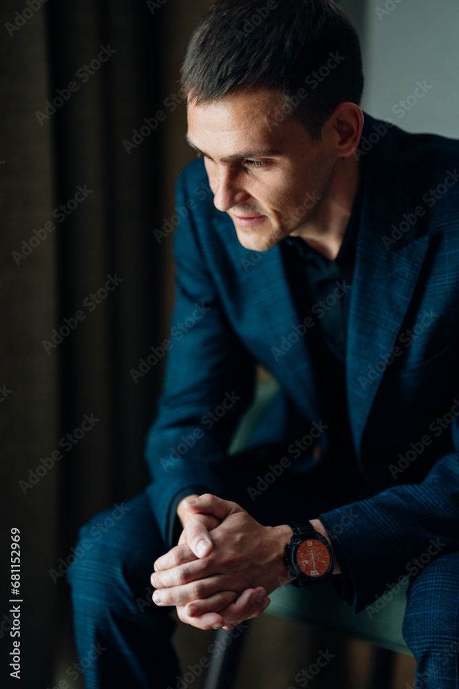 Portrait of a young man in a plaid suit on a chair. Business portrait. 