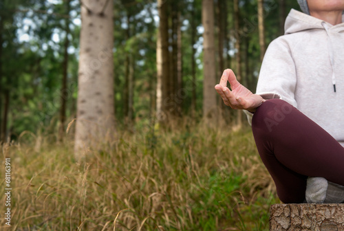 Close up of a woman in lotus position with yoga hands in a forest.