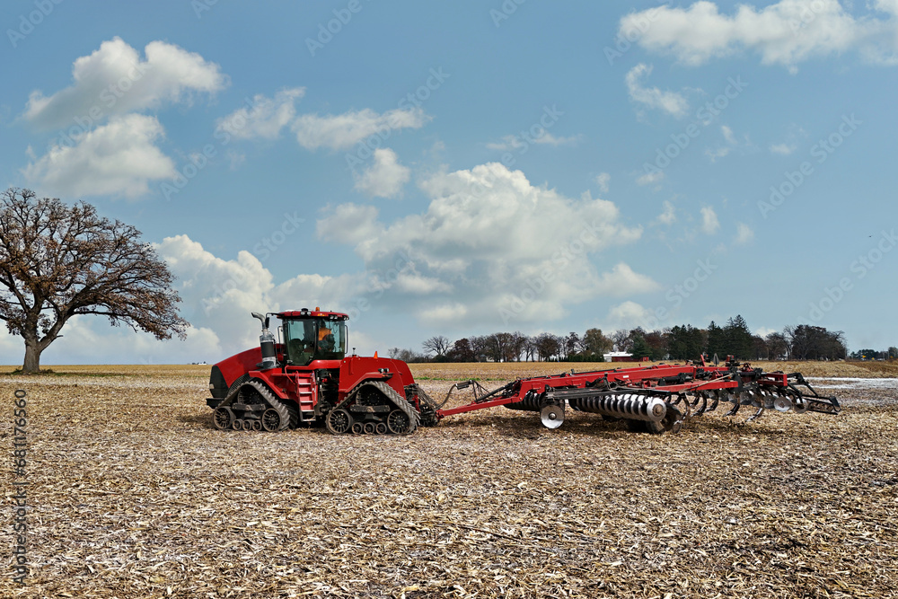Obraz premium Large red tracked tractor getting ready to cultivate a field with a chisel plough