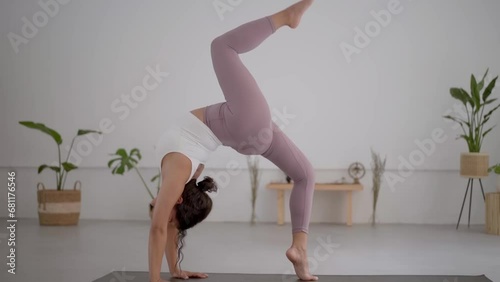 Full body side view of a young blonde woman in a red sports outfit exercising in a modern yoga or pilates centre or at home. Doing the bridge pose, Urdhva Dhanurasana. Healthy living and self-care. photo