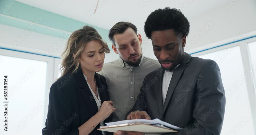 As the couple eagerly listens, the African real estate agent points out the intricate details on the plan, explaining how the untouched building can be customized to reflect their unique style.