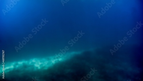Abstract blurred underwater shot of sea bottom and sun rays shining through water surface.