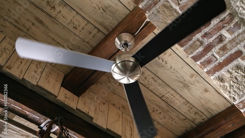 Old ceiling fan lamp spinning in the antique interior with brick walls and wooden roof photo
