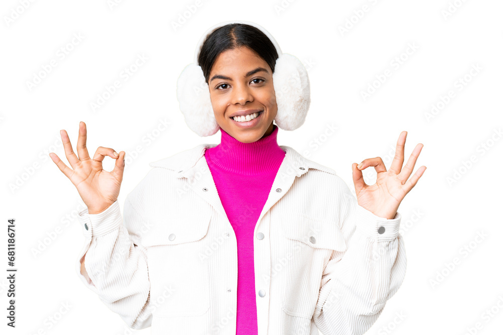 Young African American woman wearing winter muffs over isolated chroma key background showing an ok sign with fingers Young African American woman wearing winter muffs over isolated chroma key background showing an ok sign with fingers