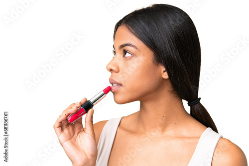 Young woman over over isolated chroma key background holding red lipstick