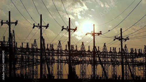 Silhouette view of an electricity-producing and distributing hub in the evening twilight light. Energy Concept electricity hub and Golden dramatic sun.