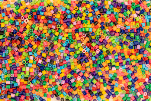 Pile of multicoloured bright Hama beads also known as craft beads for making cute designs before ironing for pile. Colorful industrial plastic granules background