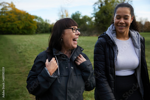 Mother laughing as she walks through park with her son and daughter.  Concept of multiracial family, motherhood, older parents and adult children.