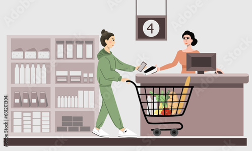 A woman with food in a cart makes a contactless payment by phone at the cash register in a supermarket. The concept of contactless payments