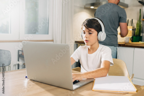 young Caucasian boy using laptop for school assignment.