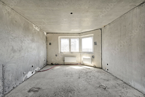 Empty living room without renovation, no repair in a new apartment building. Living room with concrete walls, floor and ceiling, no plaster